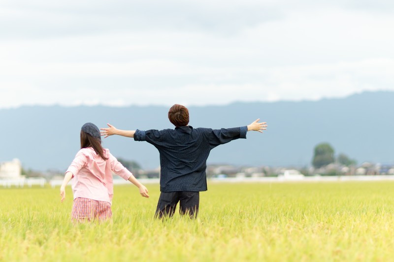 田んぼの中で手を広げて深呼吸する男女